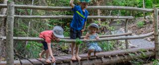 Kinder spielen am Waldbach auf einer Brücke