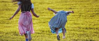 Kinder in Tracht springen auf der Wiese