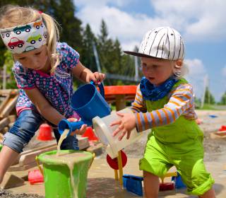 Kinder spielen in Sandkasten mit Wasser