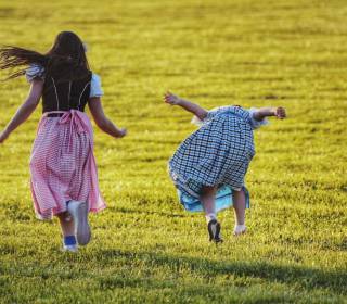 Kinder in Tracht springen auf der Wiese